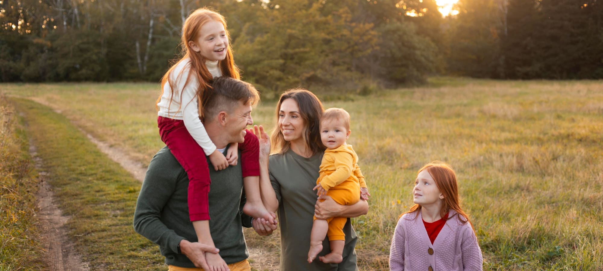 Famille nombreuse avec trois enfants dans un champ au coucher du soleil