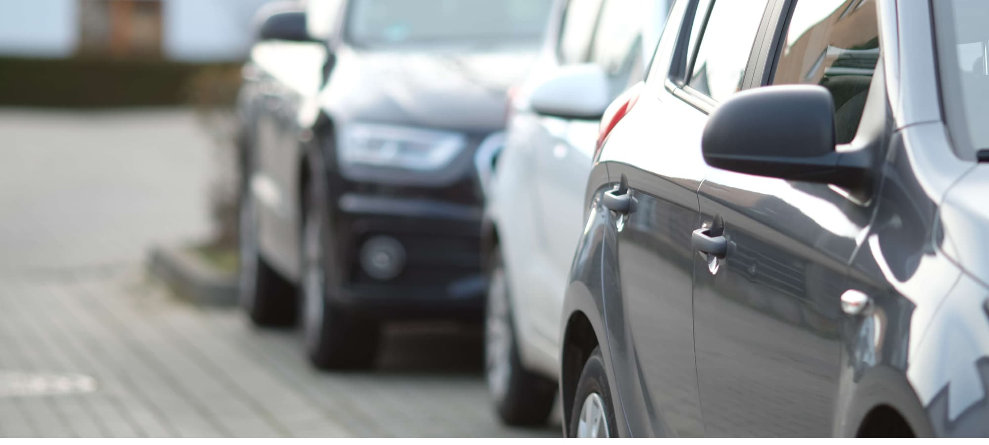 File de voitures garées en voirie dans une rue de Liège pour illustrer les zones de stationnement gratuit.
