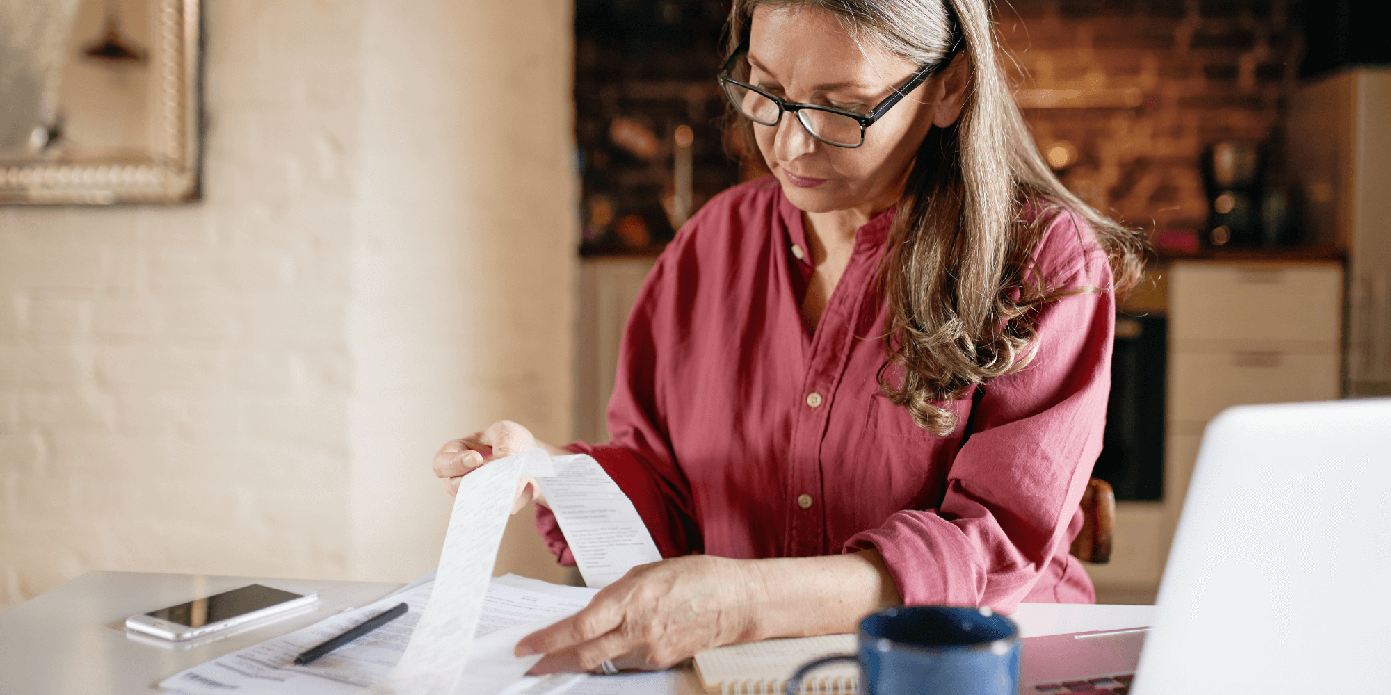 Personne remplissant une déclaration fiscale préremplie en ligne sur ordinateur en Belgique, avec documents, calculatrice et symbole de l’euro.